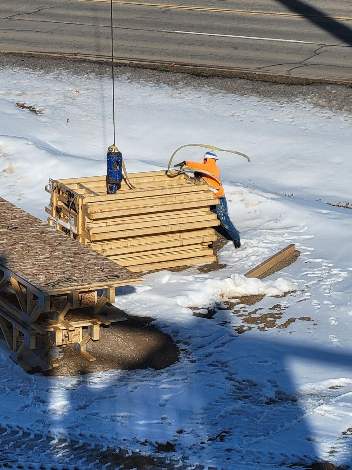 A man is lifting a stack of wooden pallets in the snow.