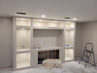 A room with a fireplace and a ladder in it is being remodeled.