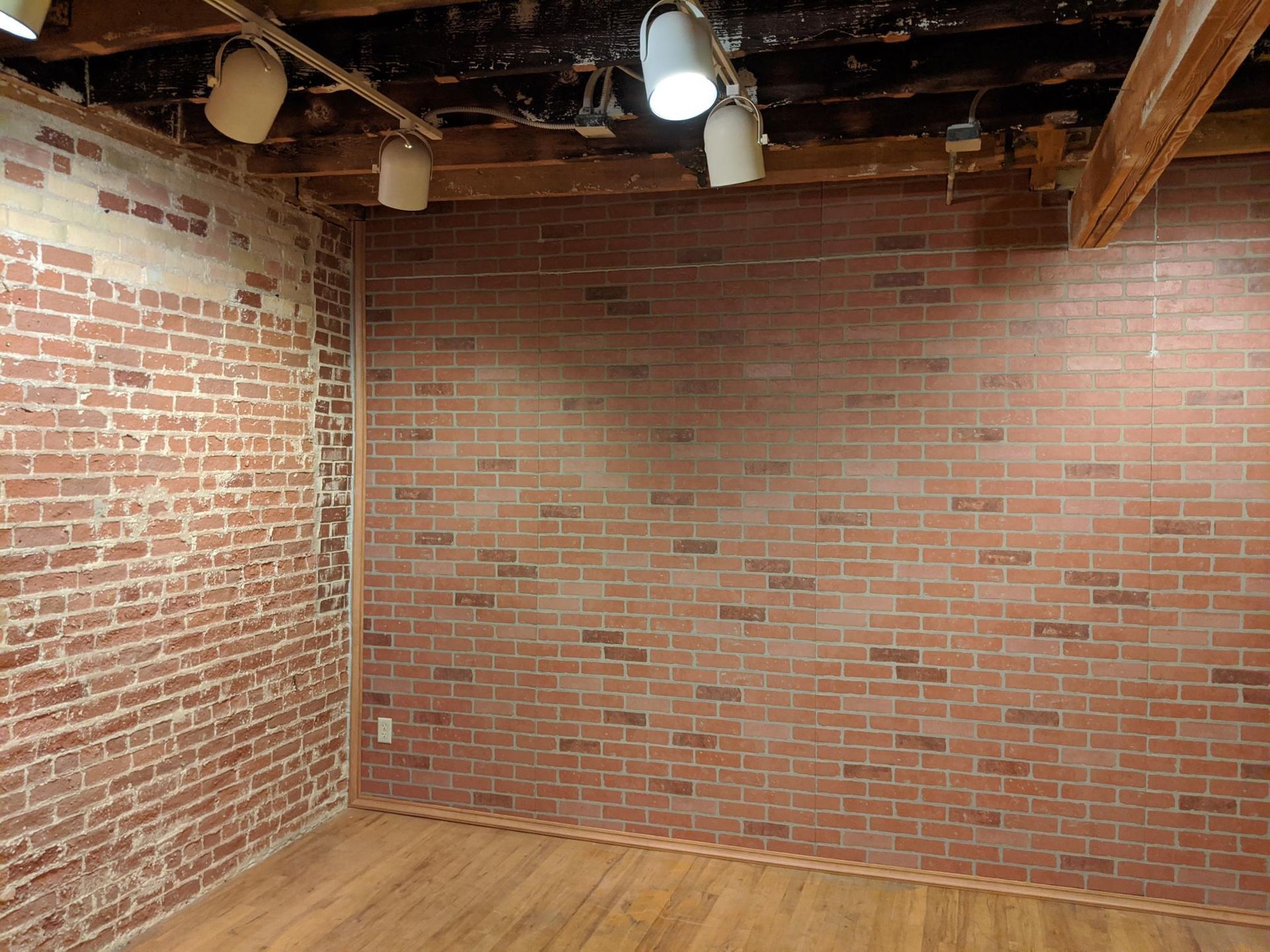 An empty room with a brick wall and wooden floor