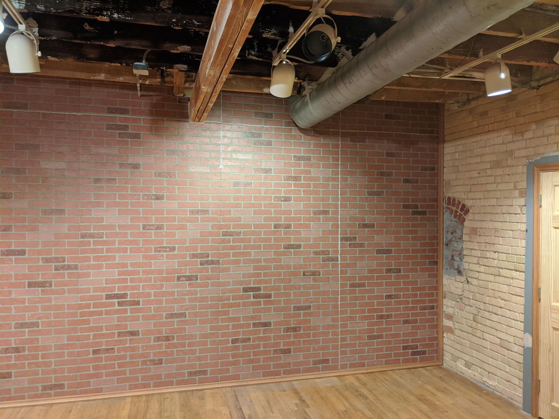An empty room with a brick wall and wooden floor