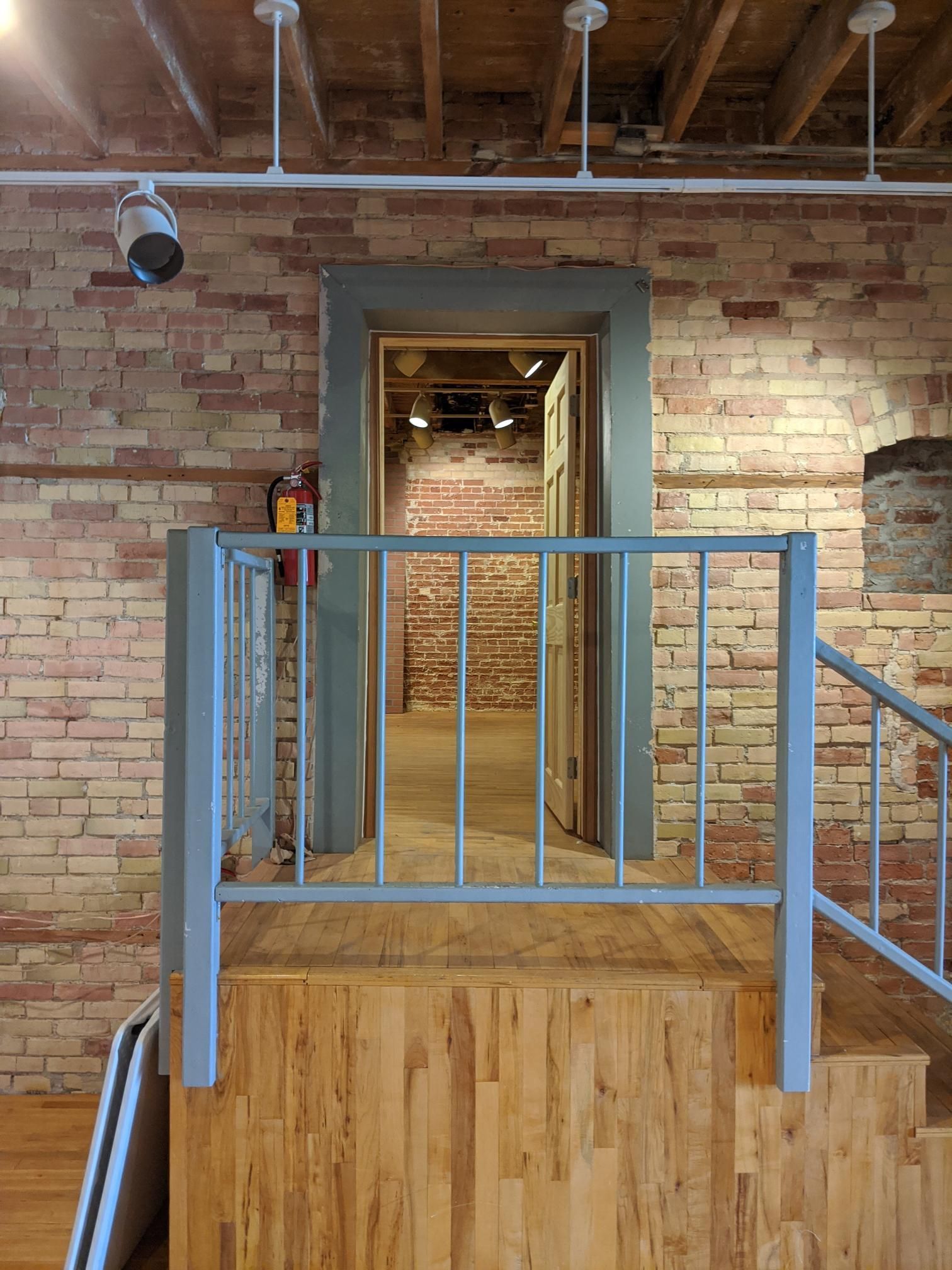 A staircase leading up to a room with a brick wall and wooden floor.