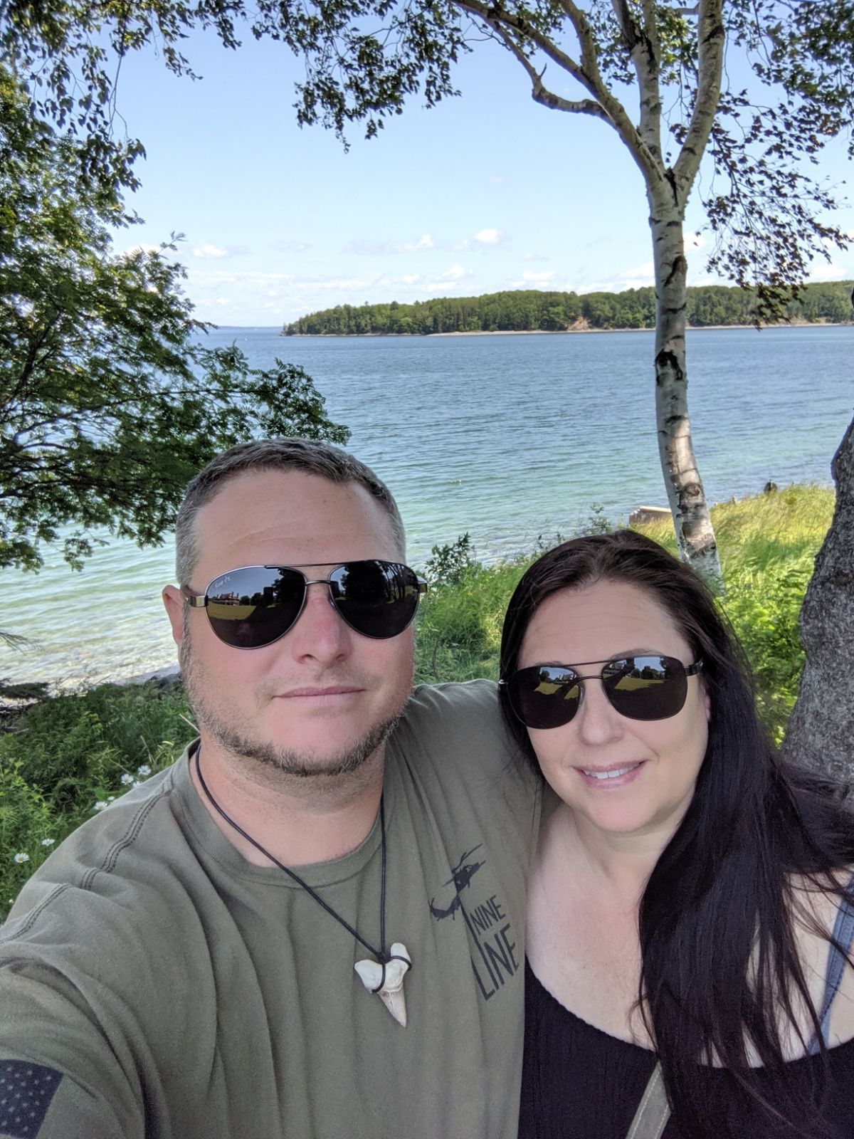 A man and a woman are posing for a picture in front of a body of water.