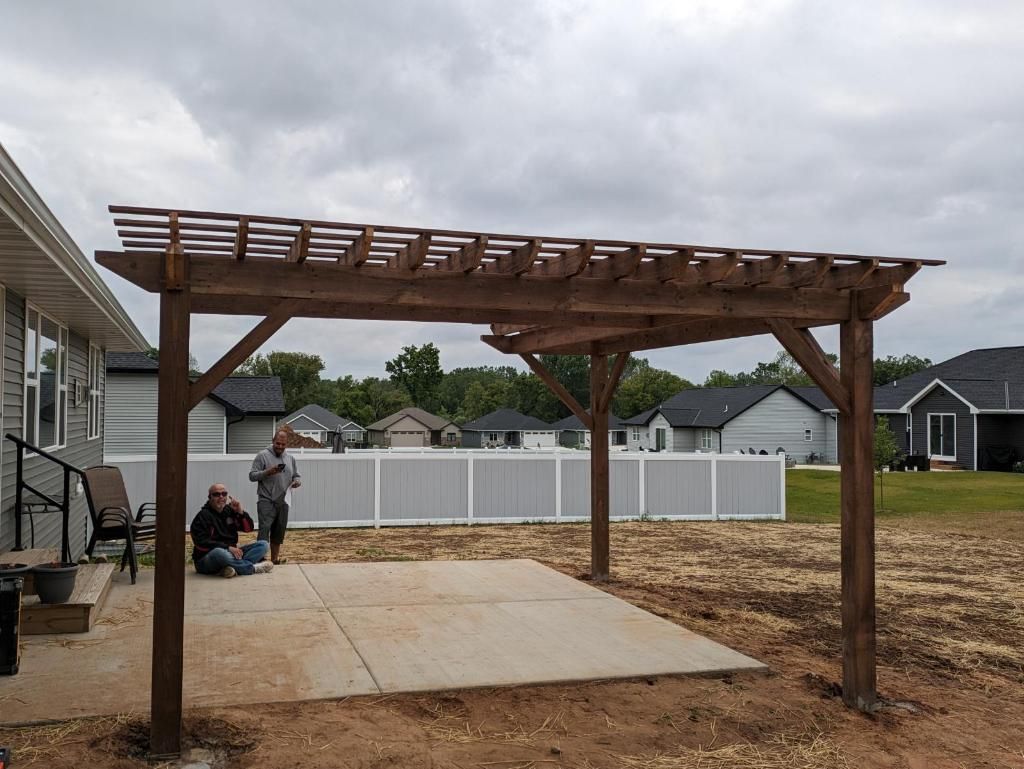 A wooden pergola is being built in the backyard of a house.