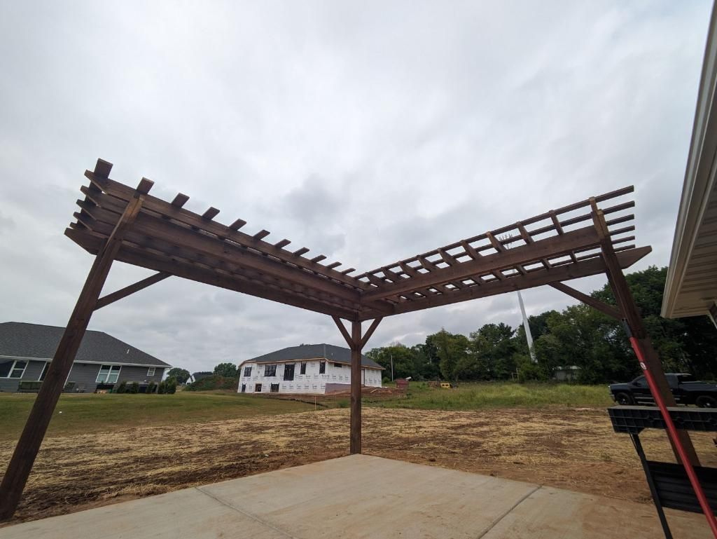 A wooden pergola is sitting on top of a concrete patio.