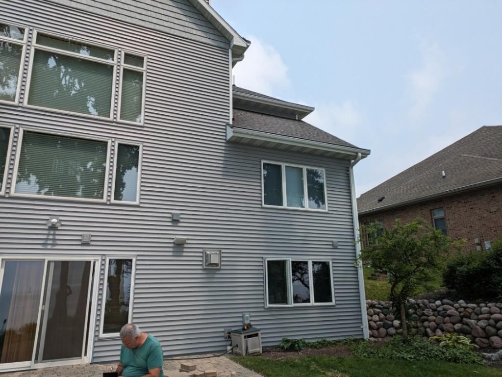 A man is sitting on a patio in front of a large house.