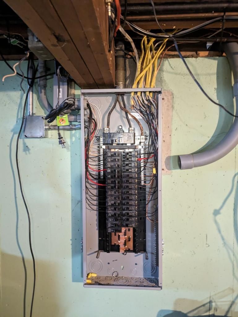 An electrical box is hanging on a wall in a basement.