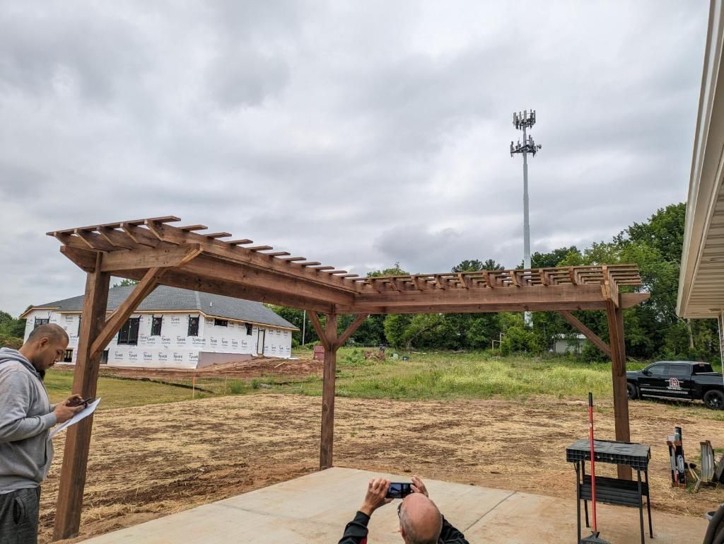 A man is taking a picture of a wooden pergola.