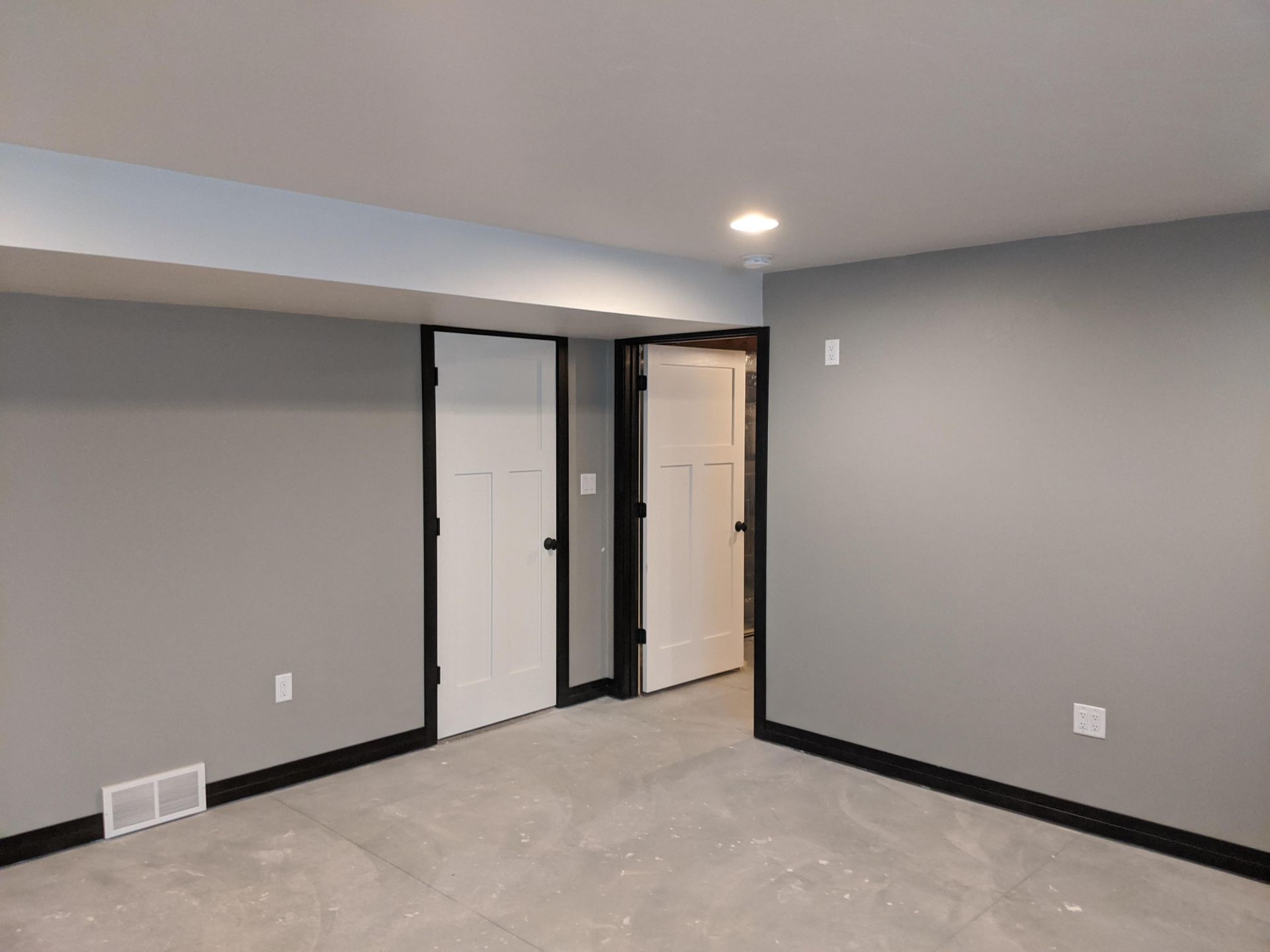 An empty basement with gray walls and a carpeted floor.