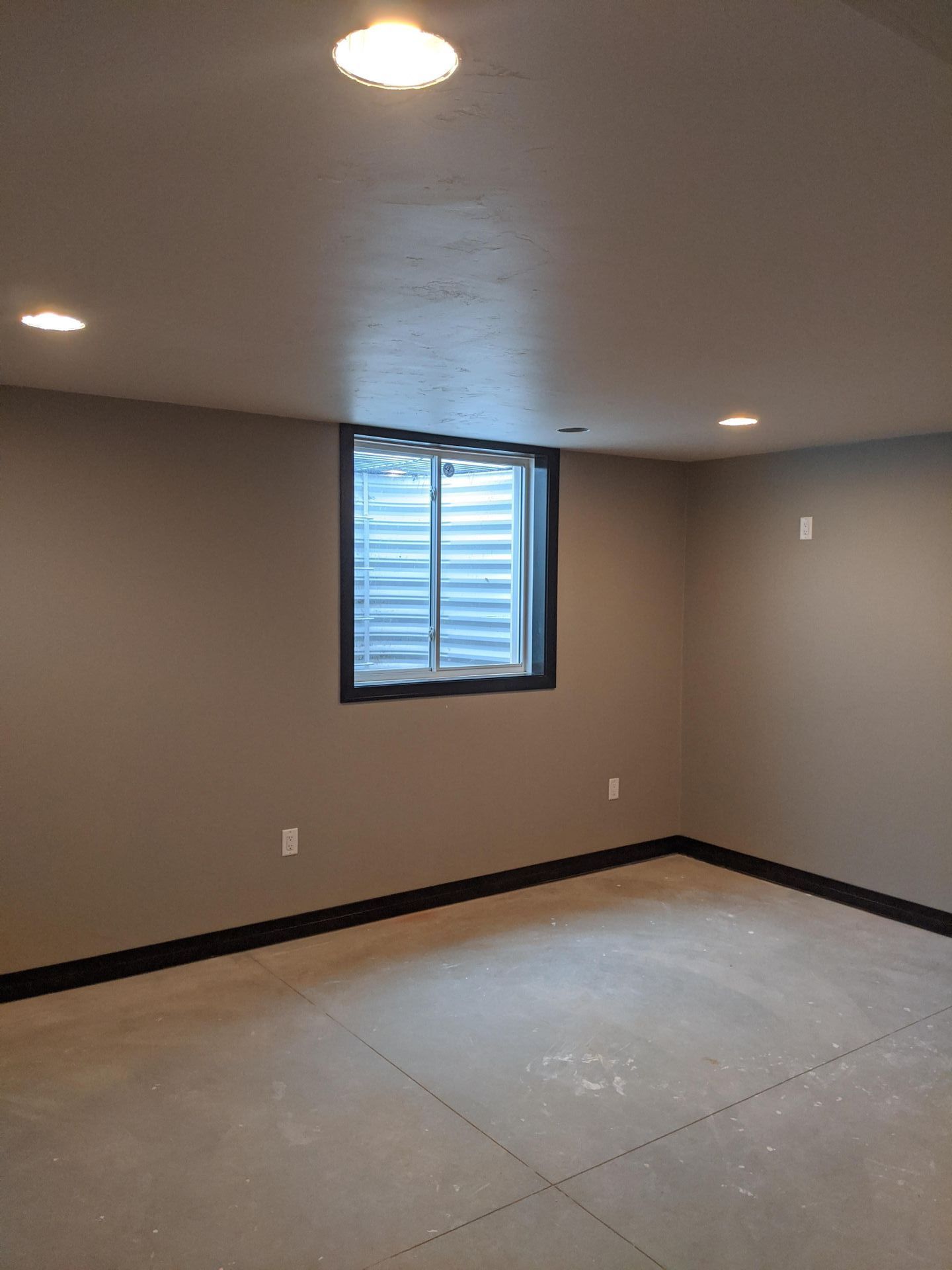 An empty basement with a window and a ceiling light.