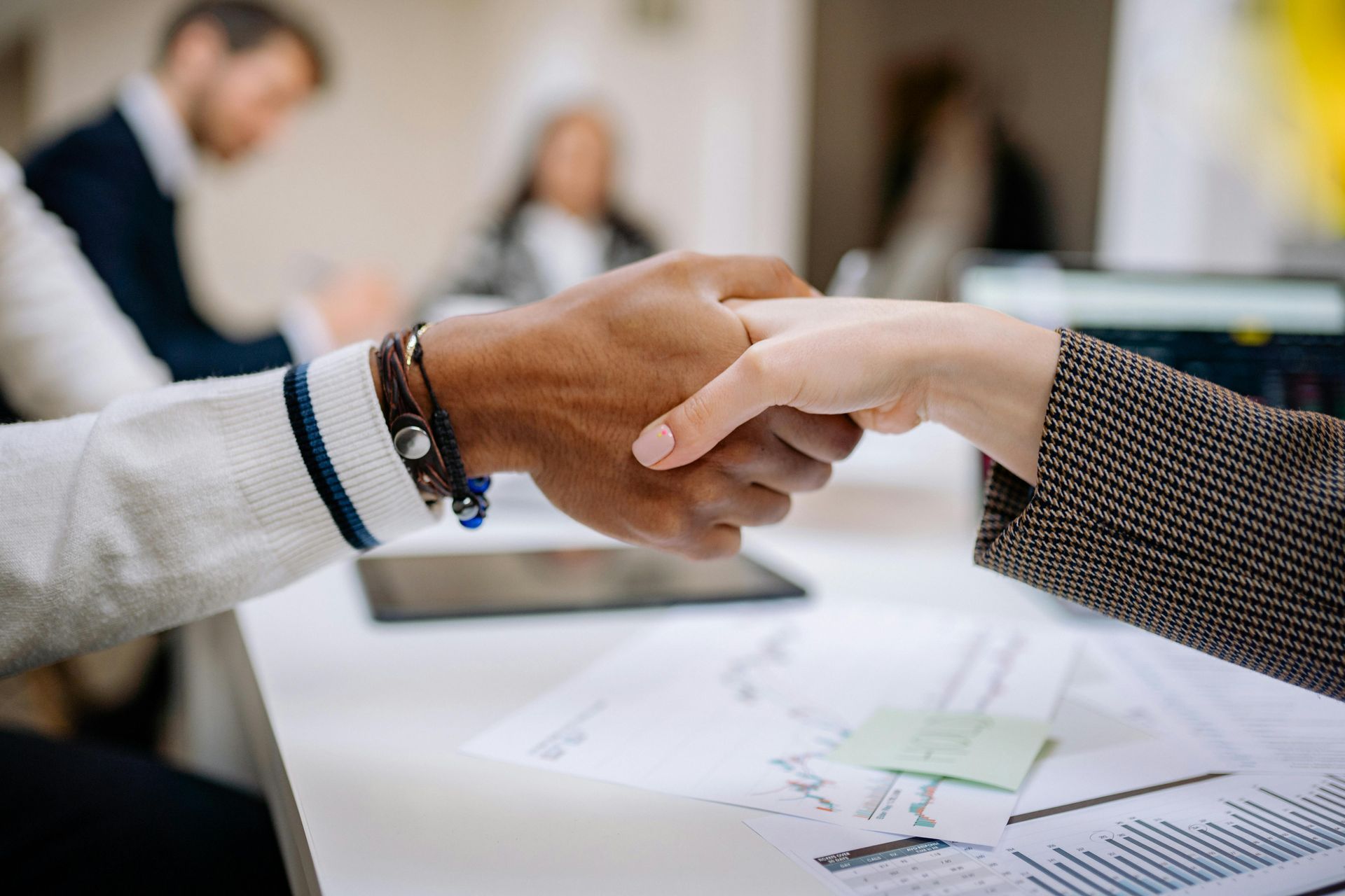 A man and a woman are shaking hands in an office.