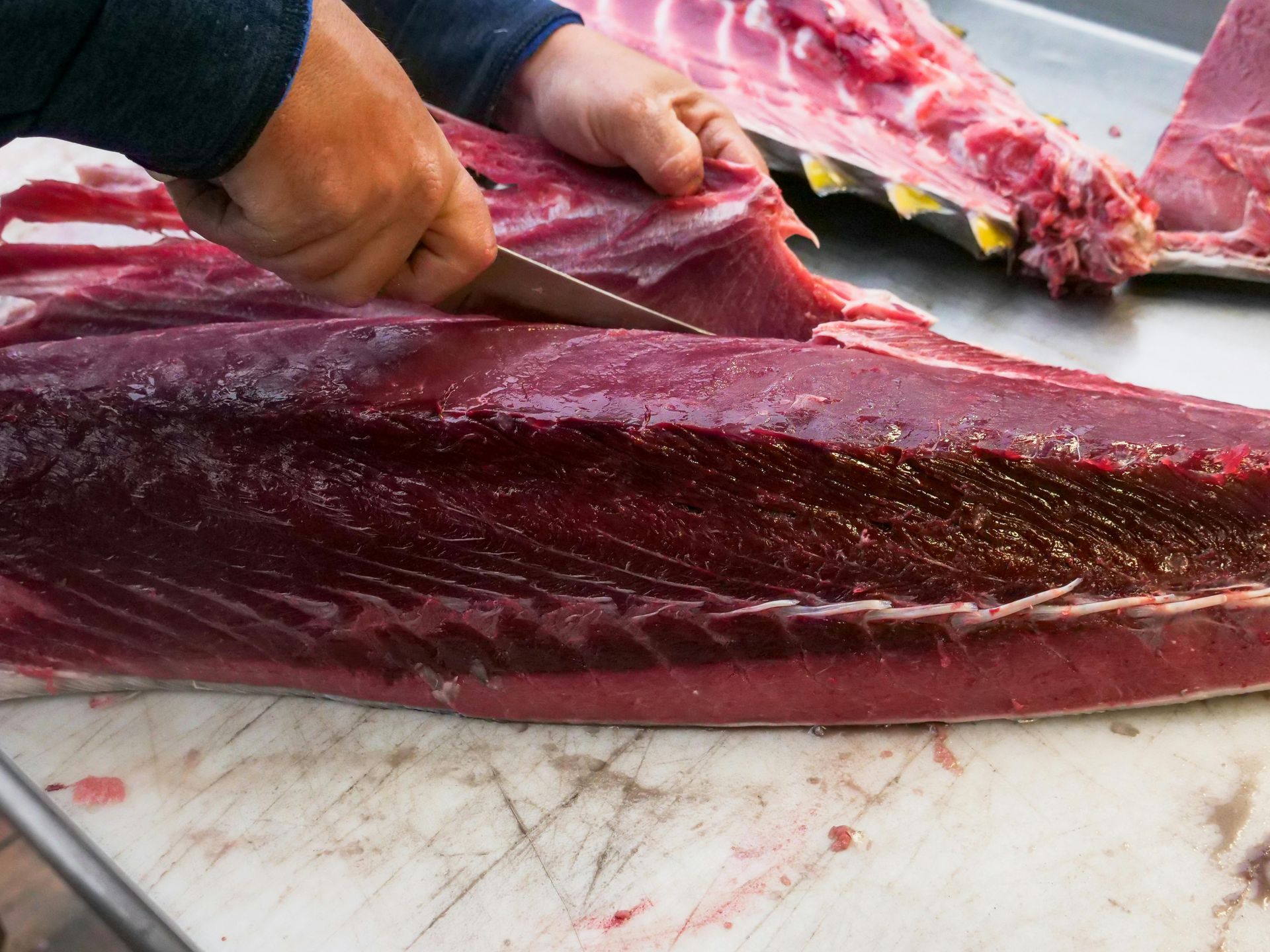 A person is cutting a large piece of meat on a cutting board.