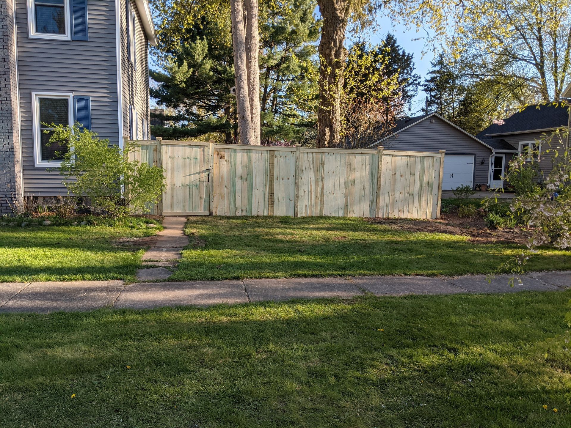 Rustic wooden fence, with weathered planks and visible grain patterns, enclosing a garden area.