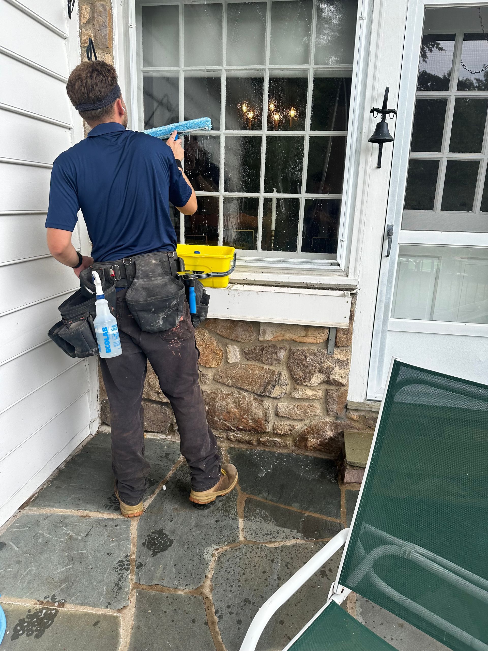 A man is cleaning a window outside of a house.