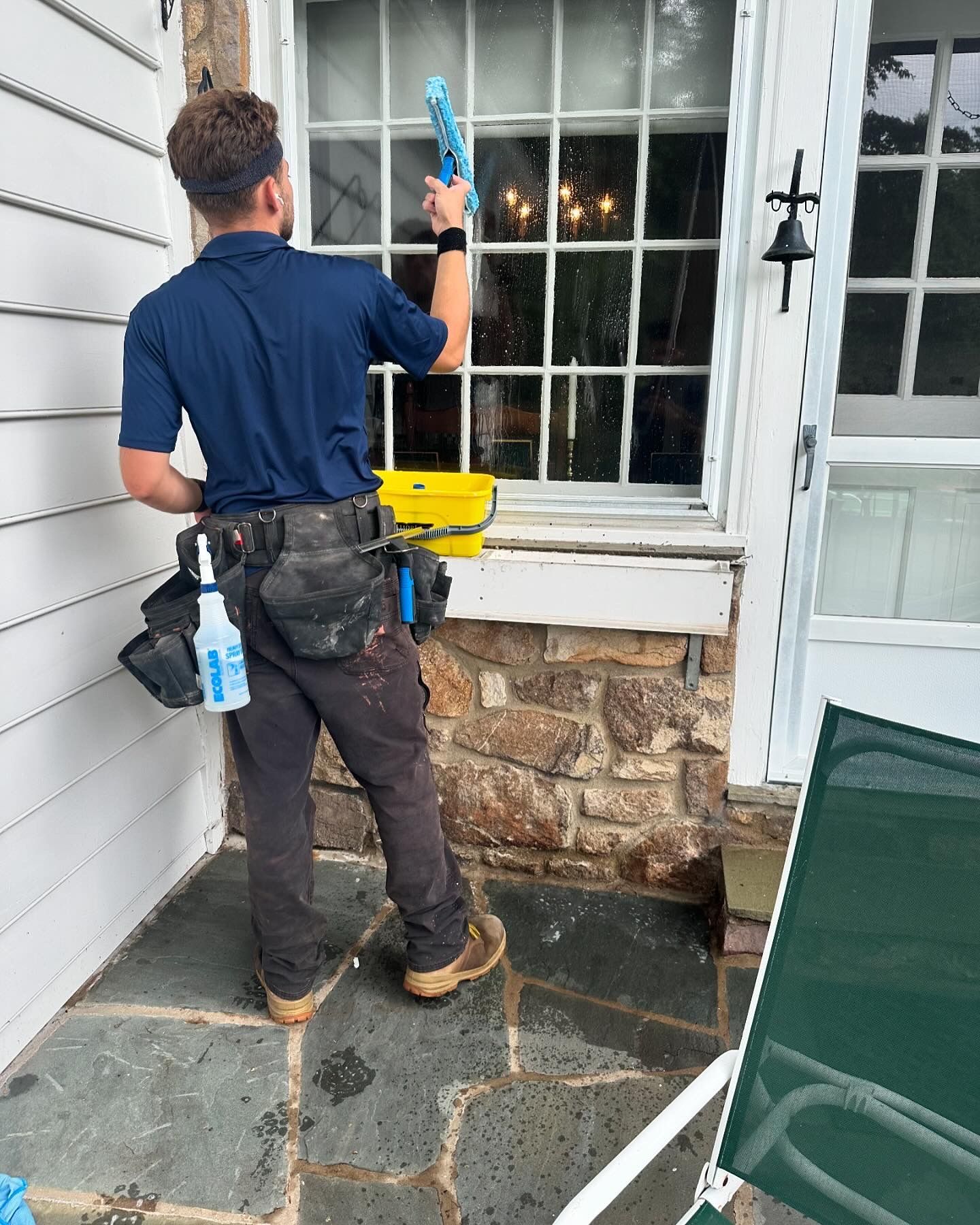 A man is cleaning a window on the side of a house.