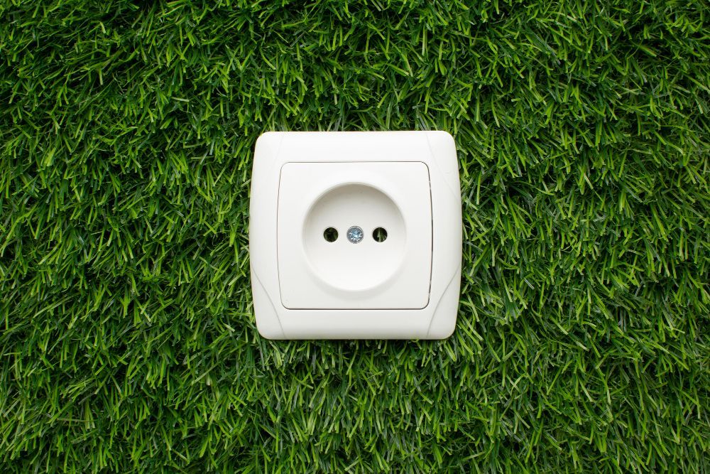 A white electrical outlet is sitting on top of a lush green field.
