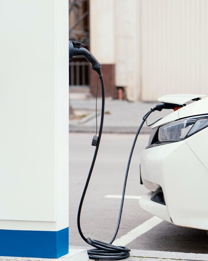 A white electric car is being charged at a charging station.
