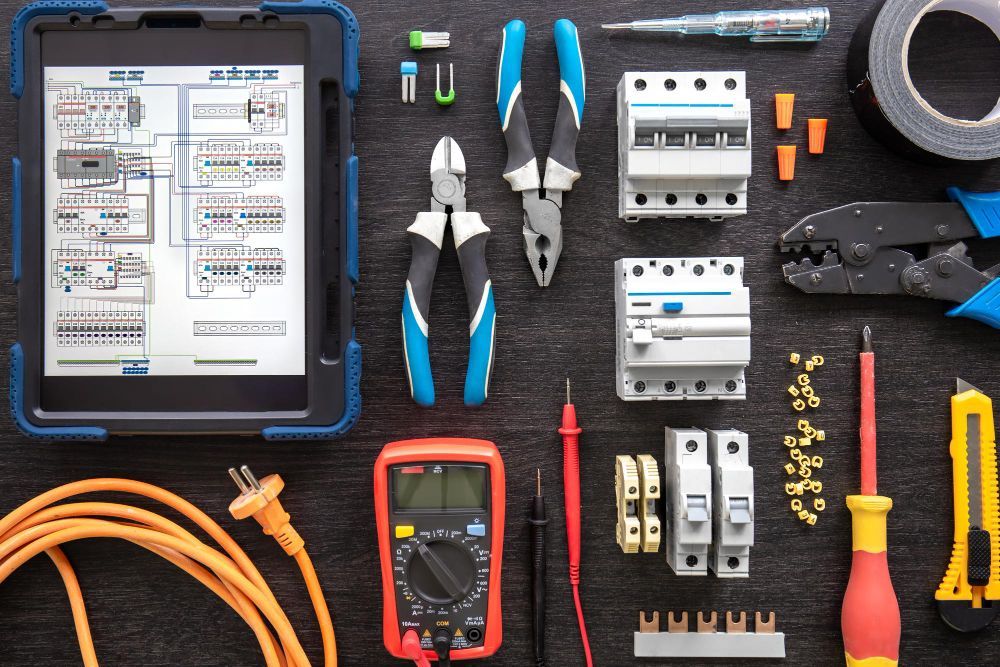 A tablet is sitting on top of a table surrounded by electrical tools.