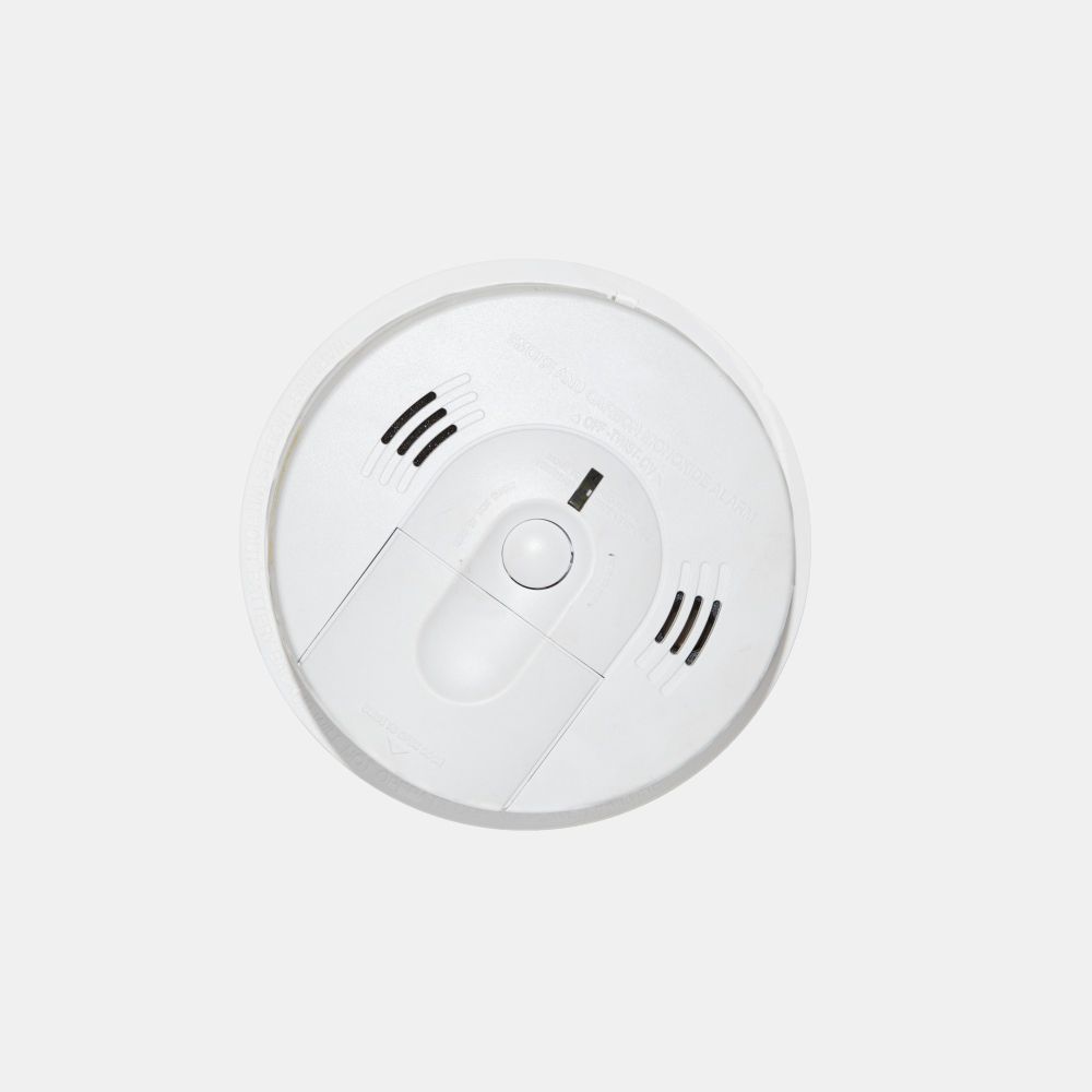 A white smoke detector is sitting on a white surface