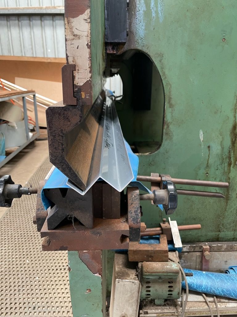 A machine is cutting a piece of metal in a factory  | Berkshire Park, NSW | V.J.S. Aluminium & Steel