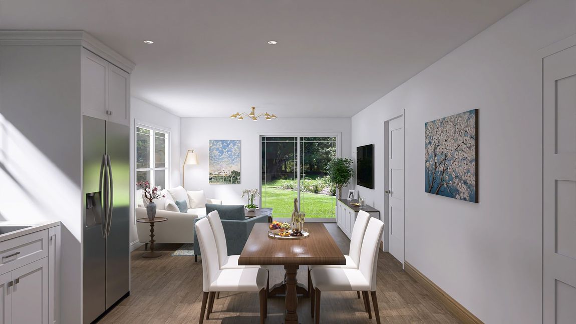 Interior view of a modern living room with dining area, kitchen, and yard view.