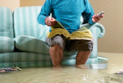 Man sitting in flooded living room using phone — Insurance in Gulfport, MS
