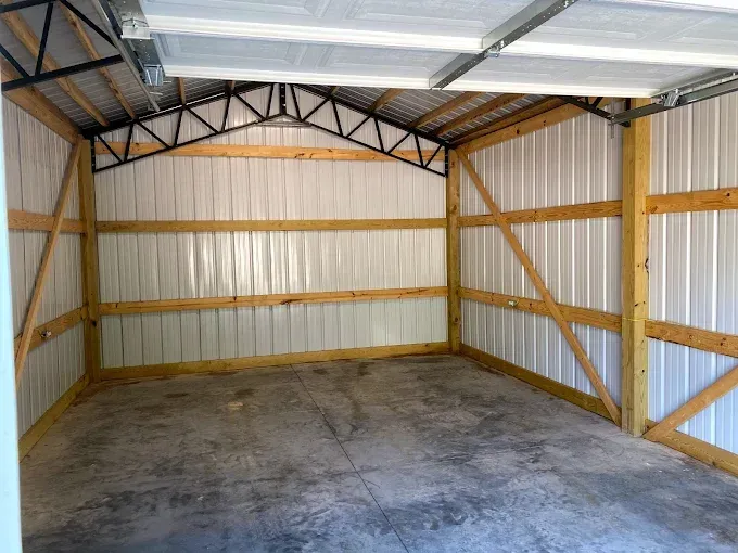 An empty metal garage with wooden beams and a concrete floor.