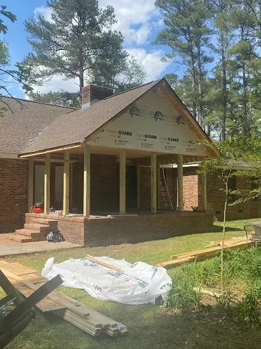 A brick house is being remodeled with a porch and a roof.