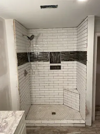 A bathroom with a walk in shower and a sink.