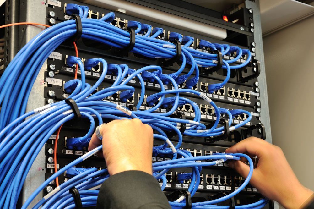 Person Is Working On A Server With Blue Wires — Telecommunication Company In Denman Prospect, ACT