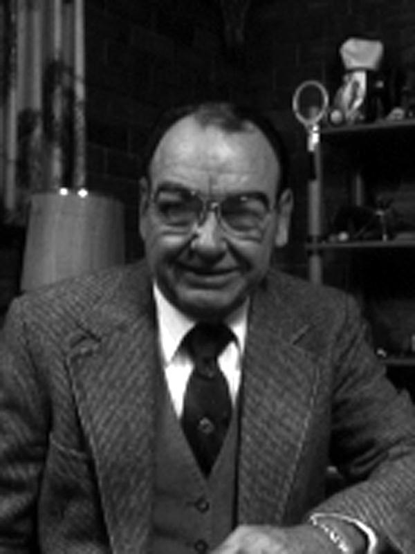 A man in a suit and tie is smiling in a black and white photo