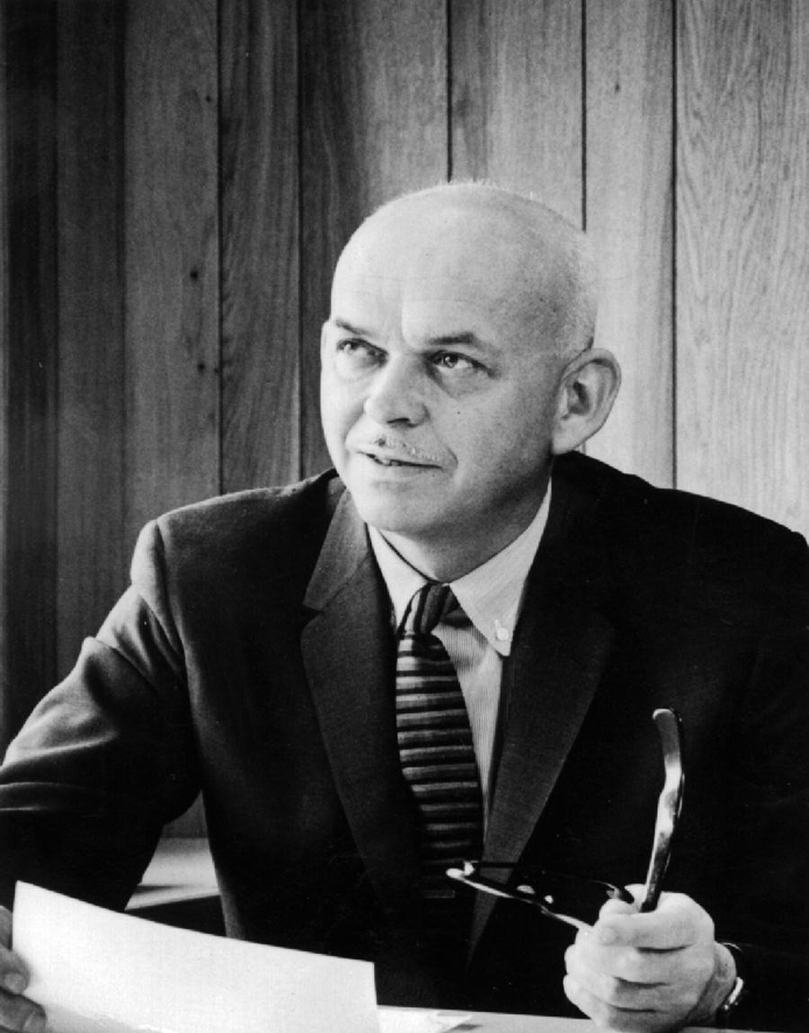 A man in a suit and tie is holding a pair of glasses