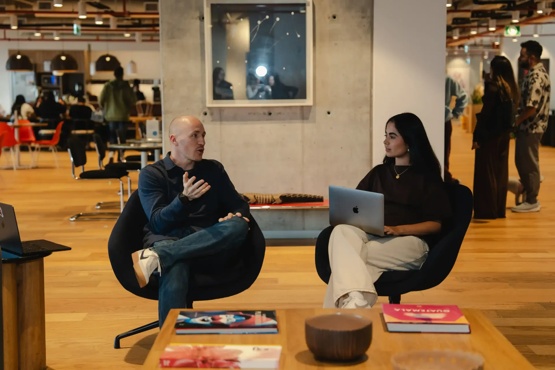 Career Coach Adam Broda And Team Member Sitting In Chairs In Common Area Talking