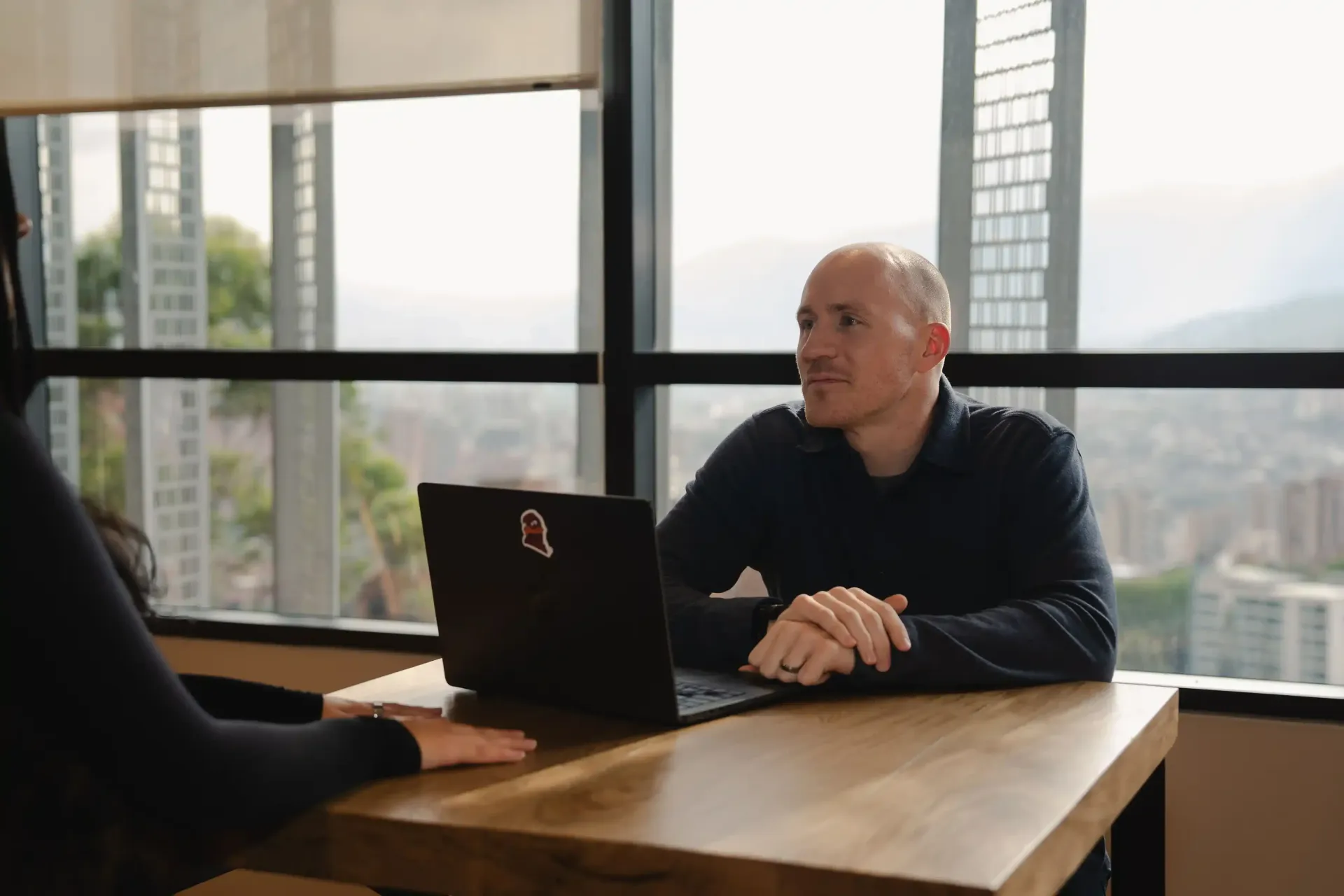 Career Coach Adam Broda Sitting At Desk Smiling Talking to Team Member