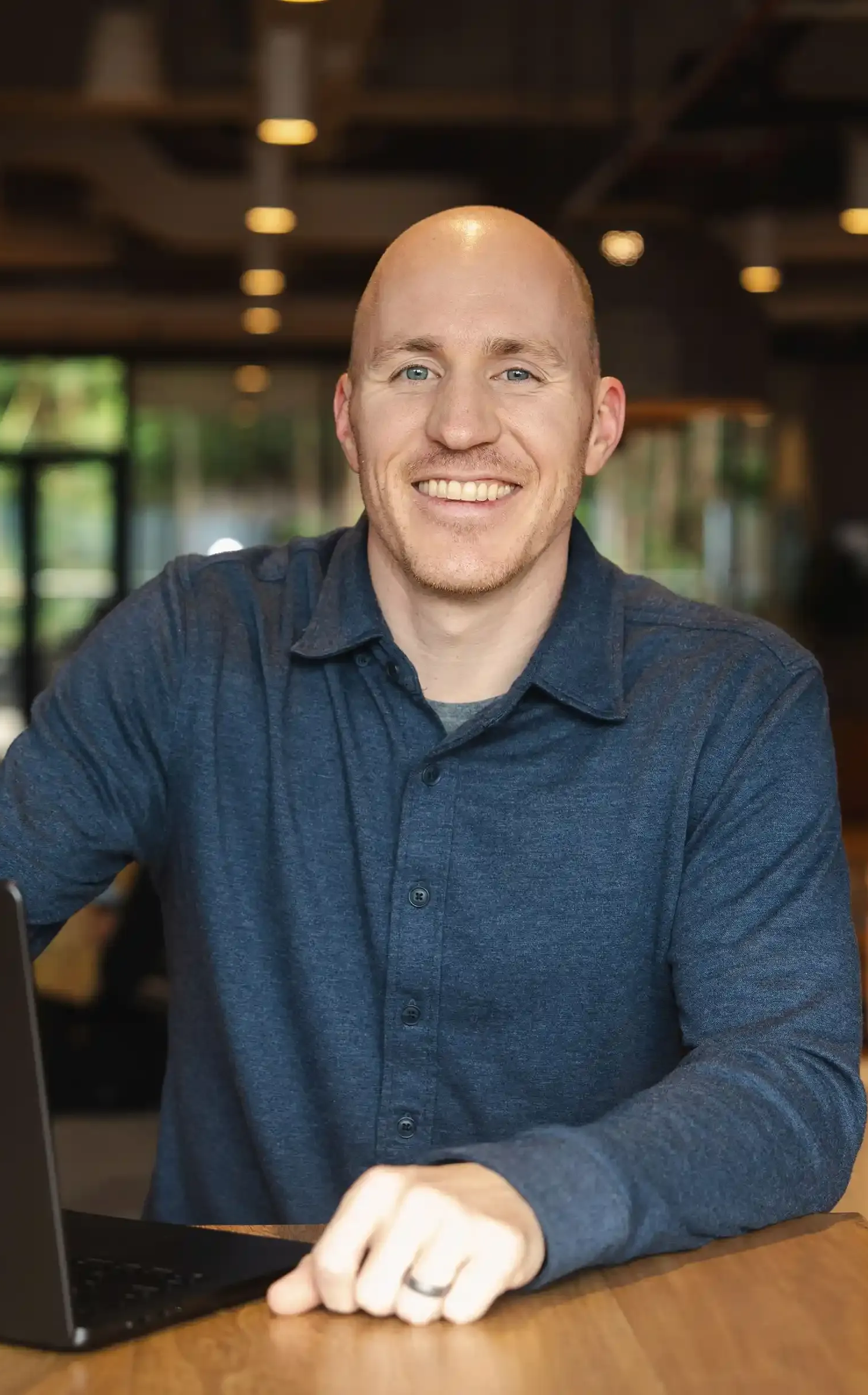 Career Coach Adam Broda Standing Next to Laptop at Table Smiling
