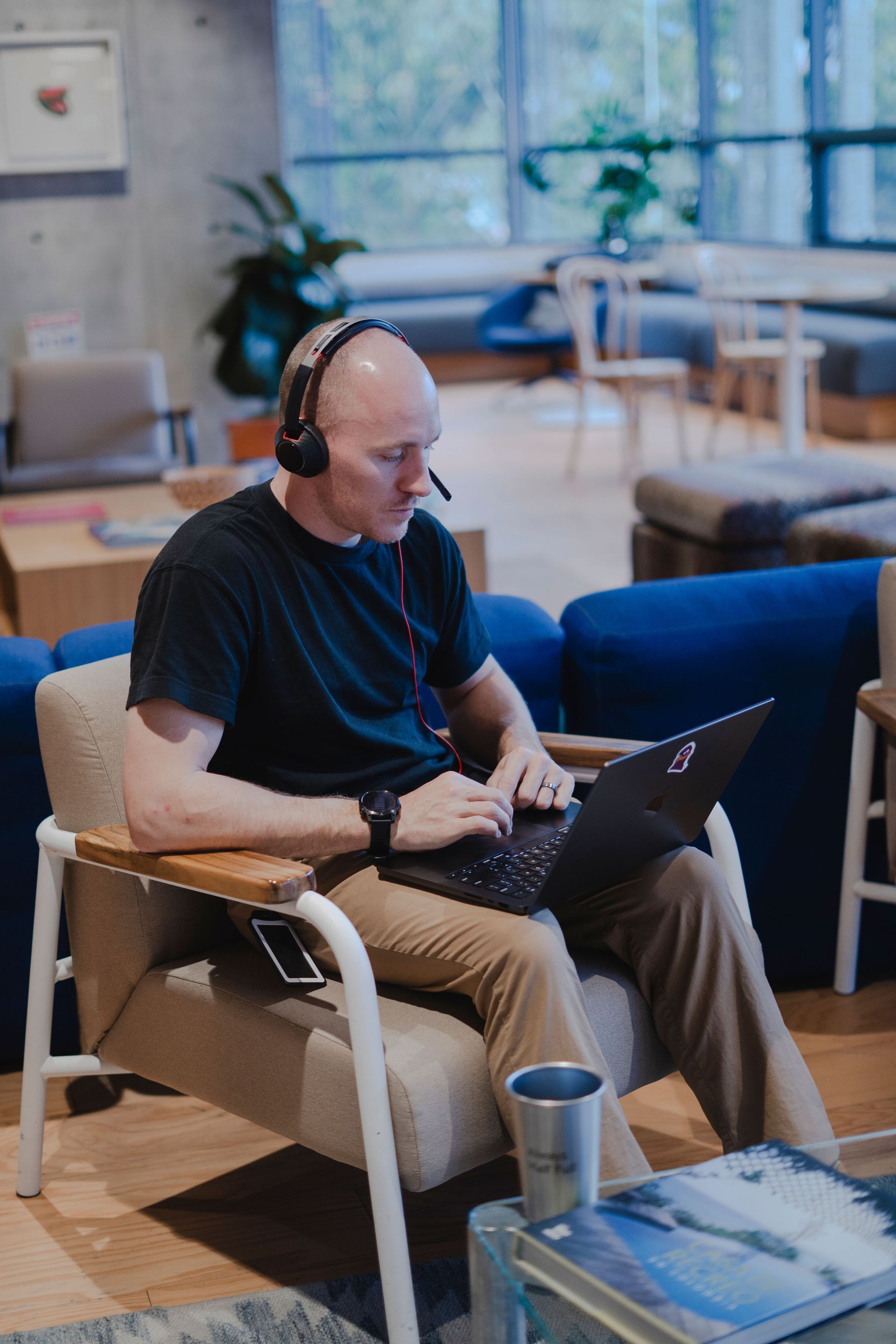 Man with headset works on a laptop in a modern office setting.