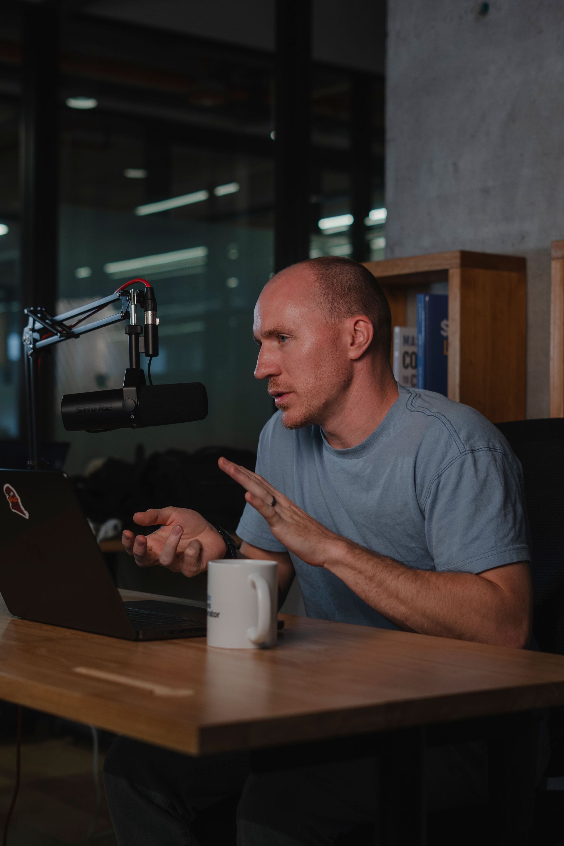 Adam Broda recording a podcast, about how to write resumes, gesturing at laptop and microphone in a studio.