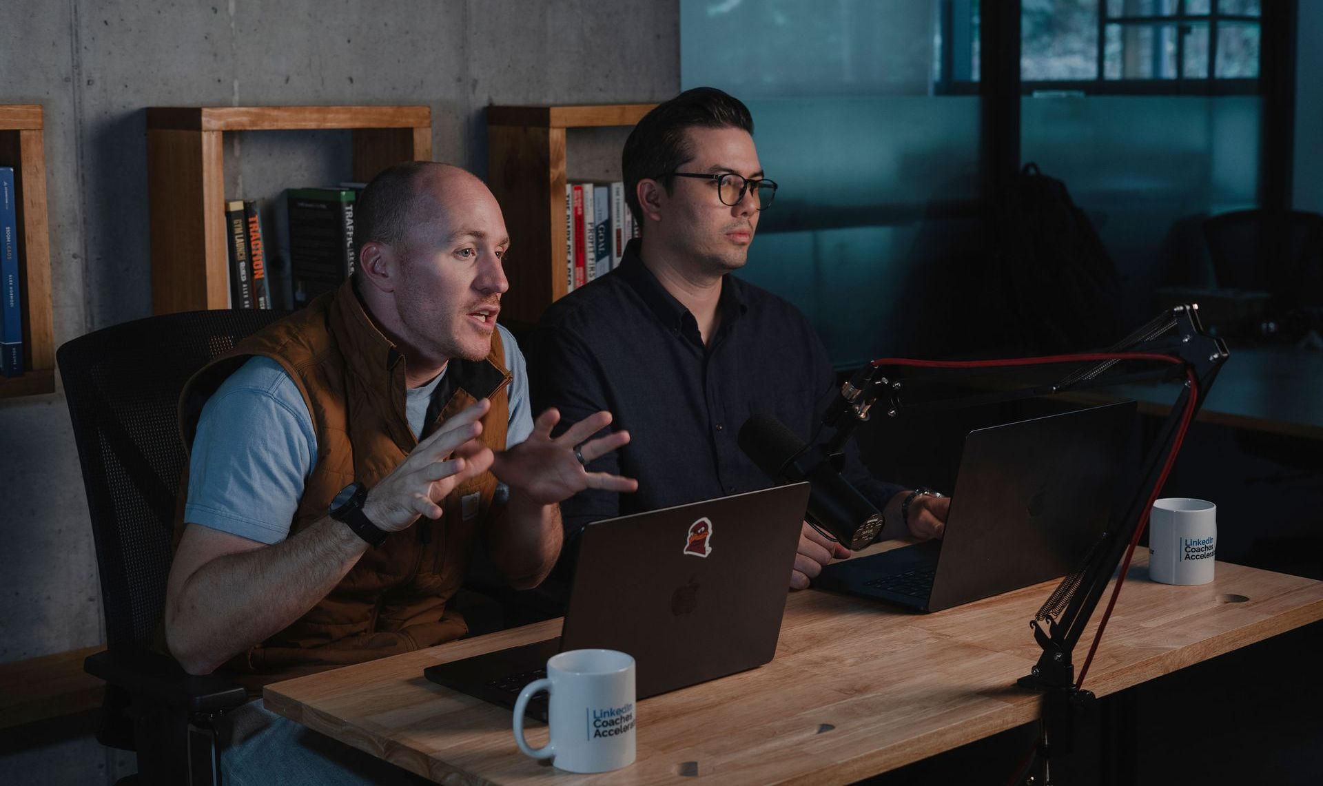 Adam Broda, top career change coach at a desk, gestures excitedly while the other looks at a laptop.