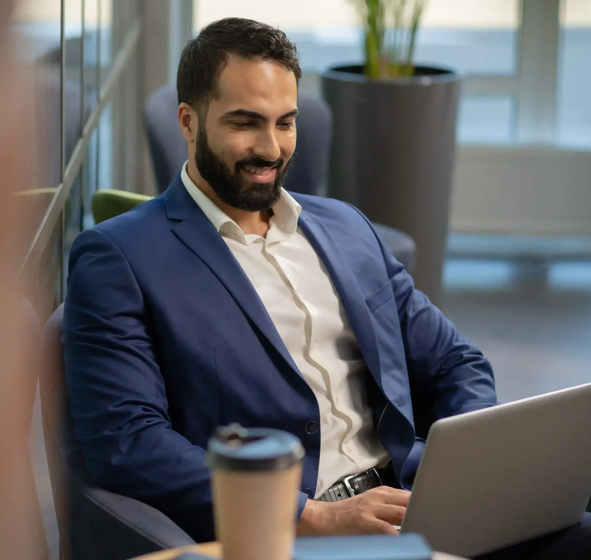 A man in a suit is sitting in front of a laptop working on his personal branding.
