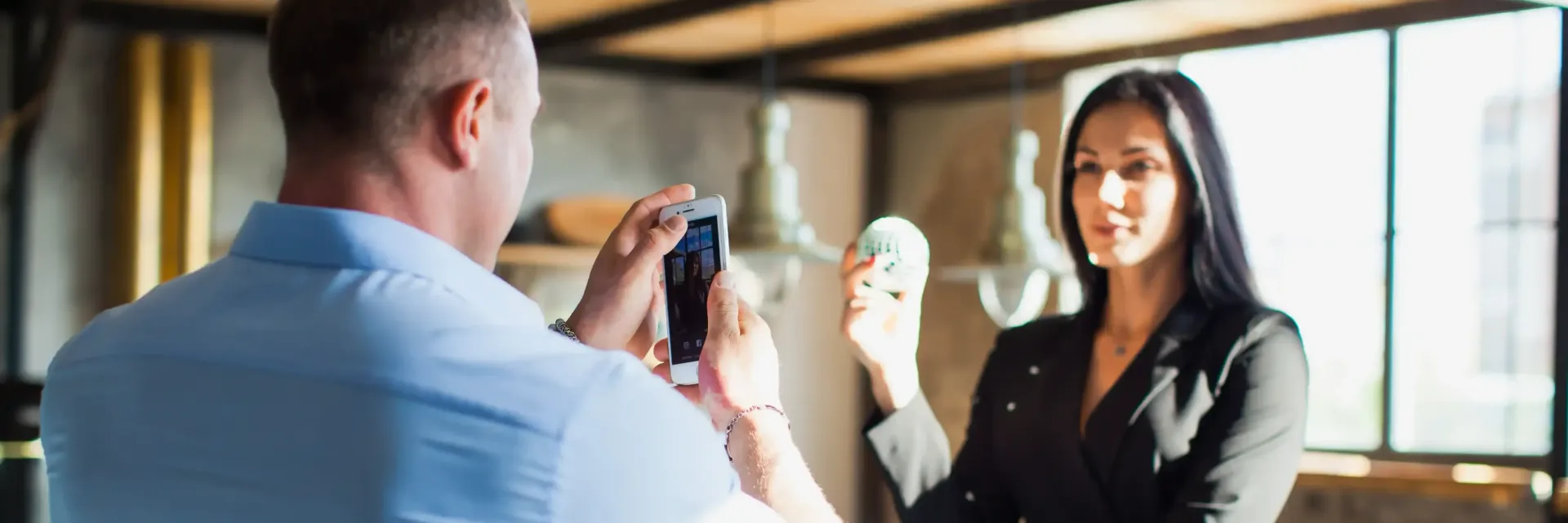 A man is taking a picture of a woman with a cell phone for her social media to boost her personal brand.