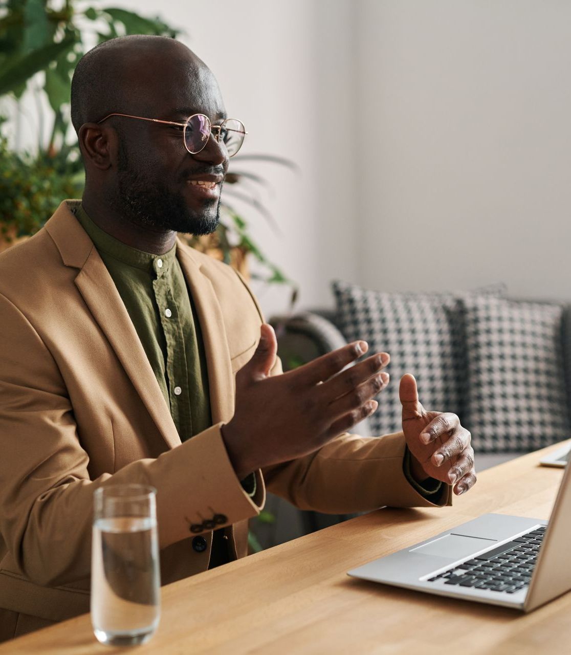 A man is sitting at a table with a laptop and a glass of water with his career coach receiving executive coaching.