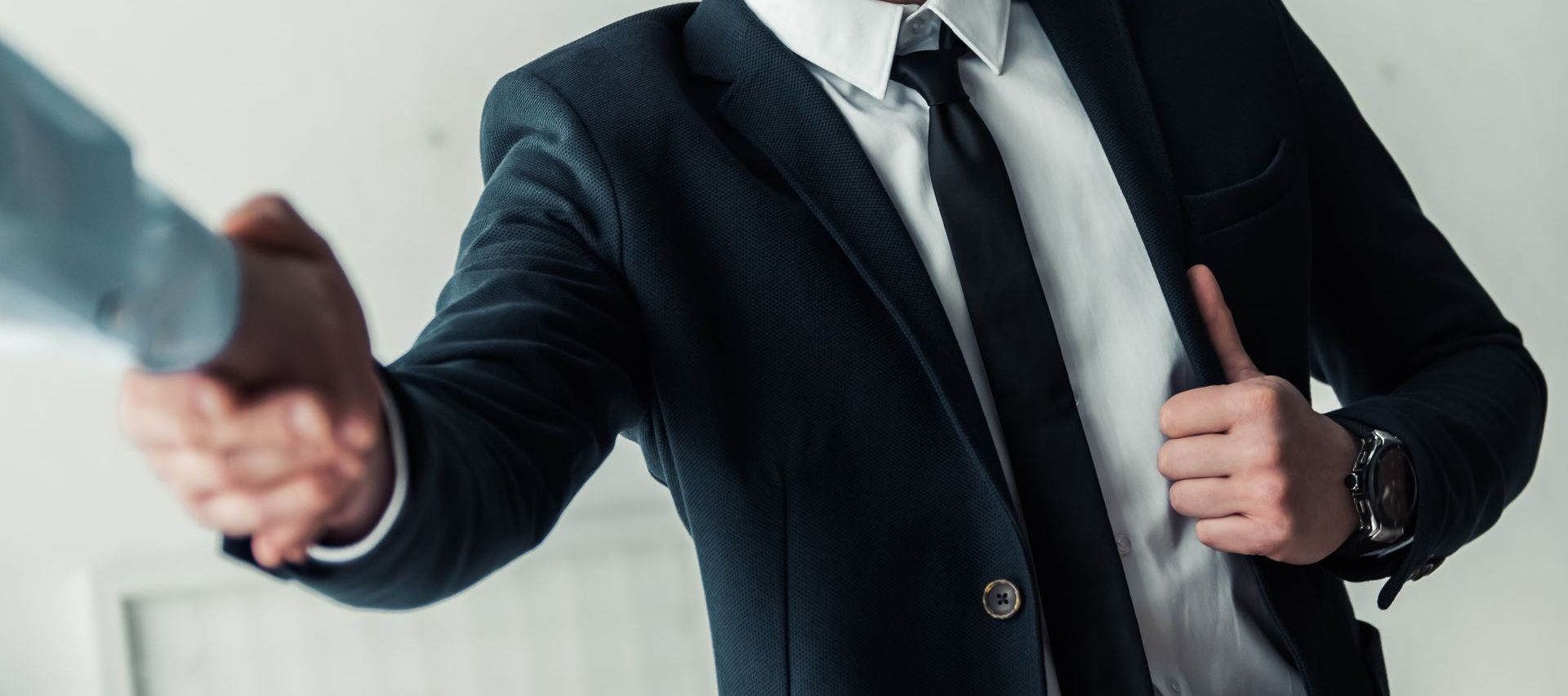 A man in a suit and tie is shaking hands with another man after being hired with the skills he learned from career coaching.