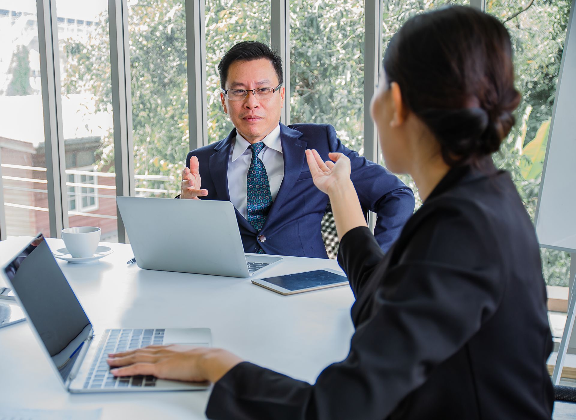 A man and a woman are sitting at a table with laptops career coaching.