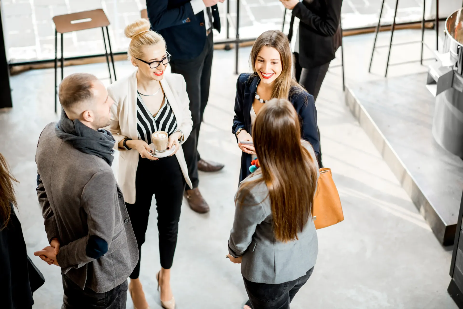 A group of people are standing around talking to each other at a networking event for senior level professionals.