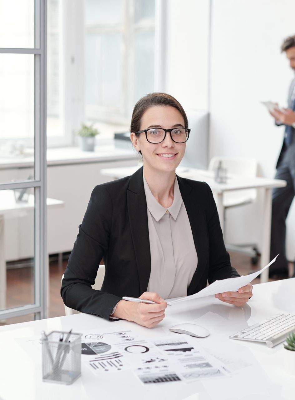 A woman is sitting at a desk in an office holding a piece of paper studying how to develop effective job search strategies for an evolving market.