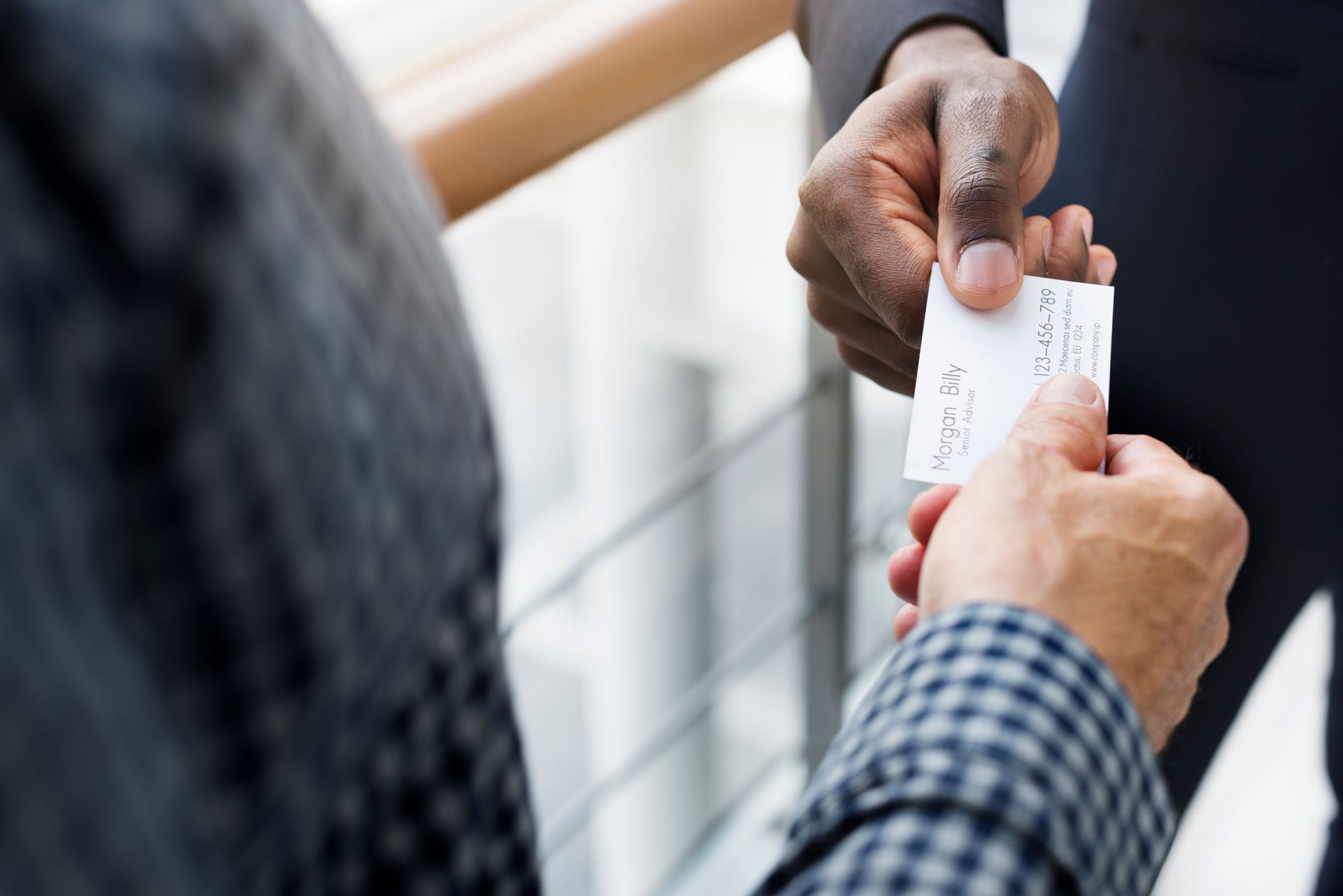 A man is handing a business card to another man for career coaching services.