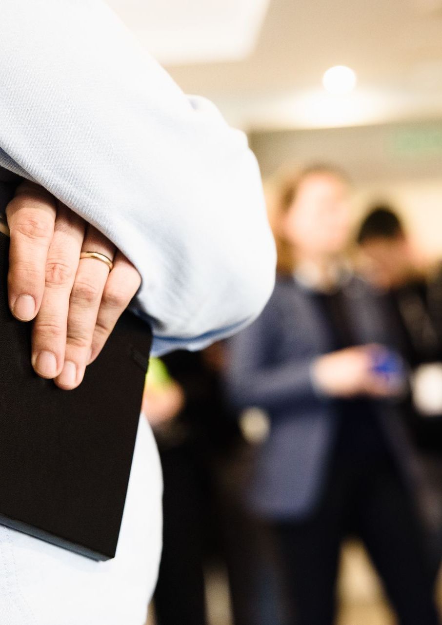 A person holding a black notebook at a networking event.