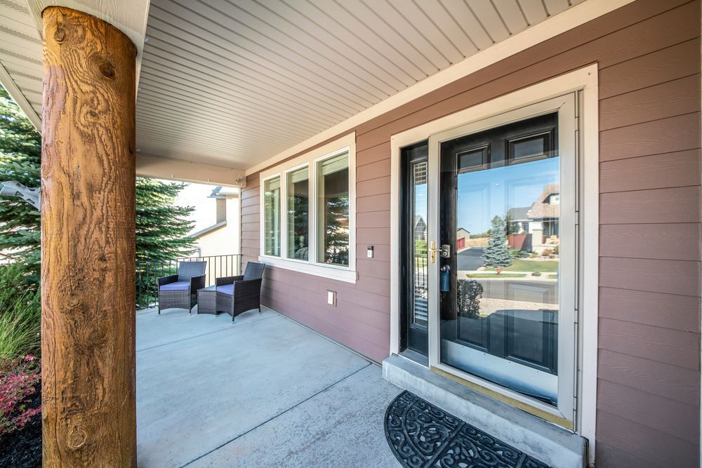 The front porch of a house with a large glass door and a wooden post.