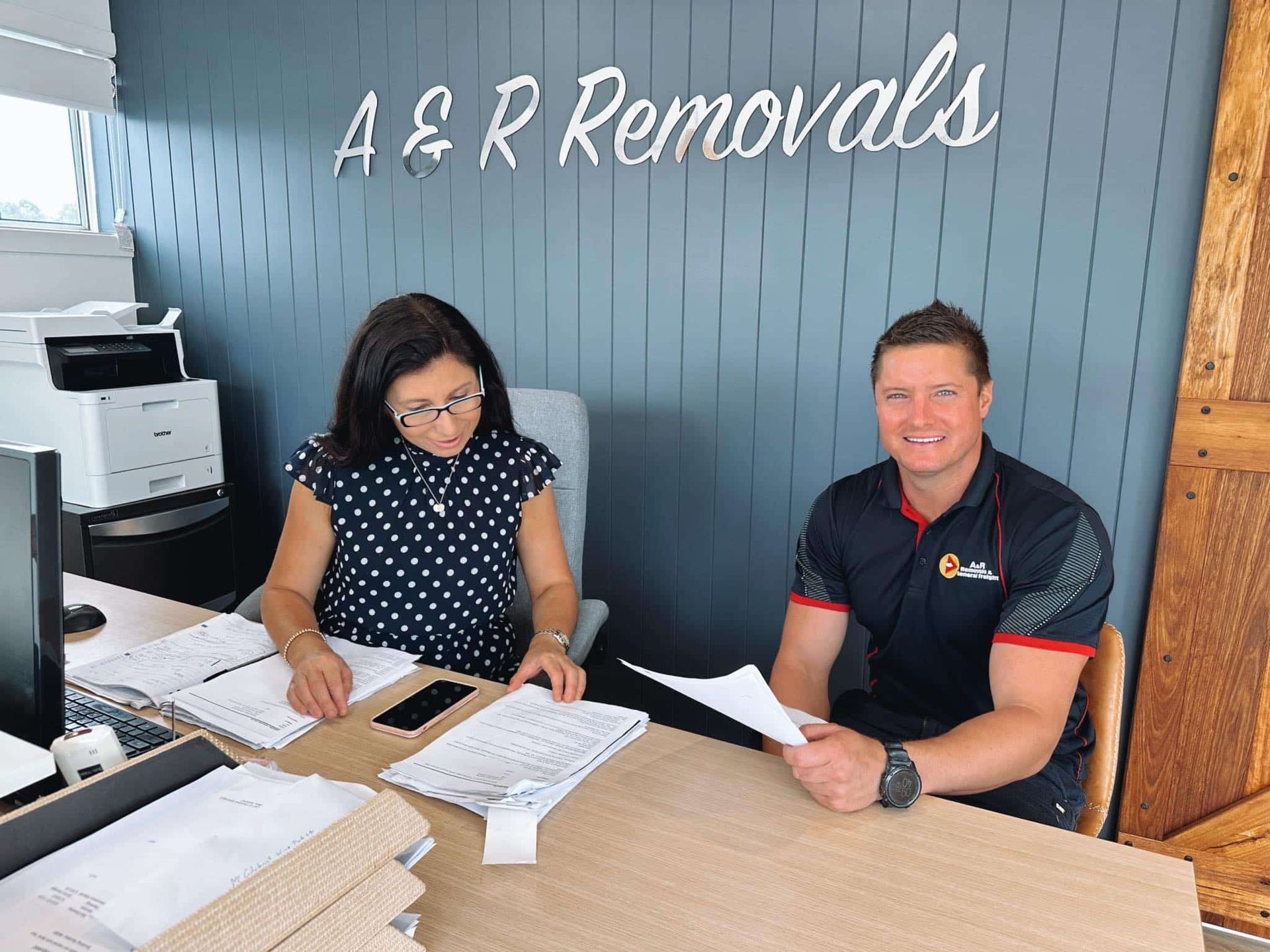 A Man and a Woman Are Sitting at a Desk — Easy Choice Removals and General Freight In Port Macquarie, NSW