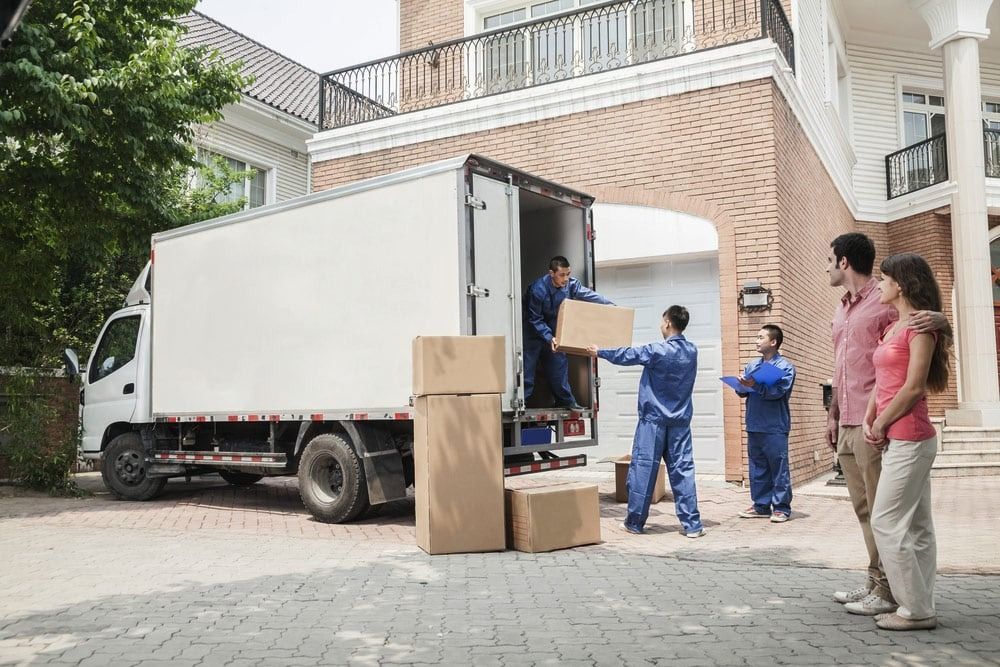 A Group of People Are Standing in Front of a Moving Truck — Easy Choice Removals and General Freight In Port Macquarie, NSW