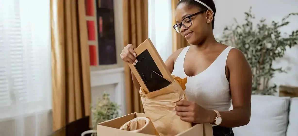 A Woman is Holding a Picture Frame — Easy Choice Removals and General Freight In Port Macquarie, NSW